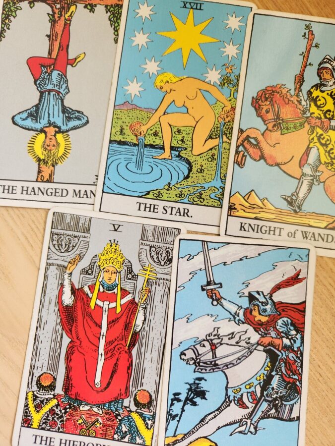 Tarot spread featuring The Star, The Hanged Man, and Knight of Wands on a wooden table
