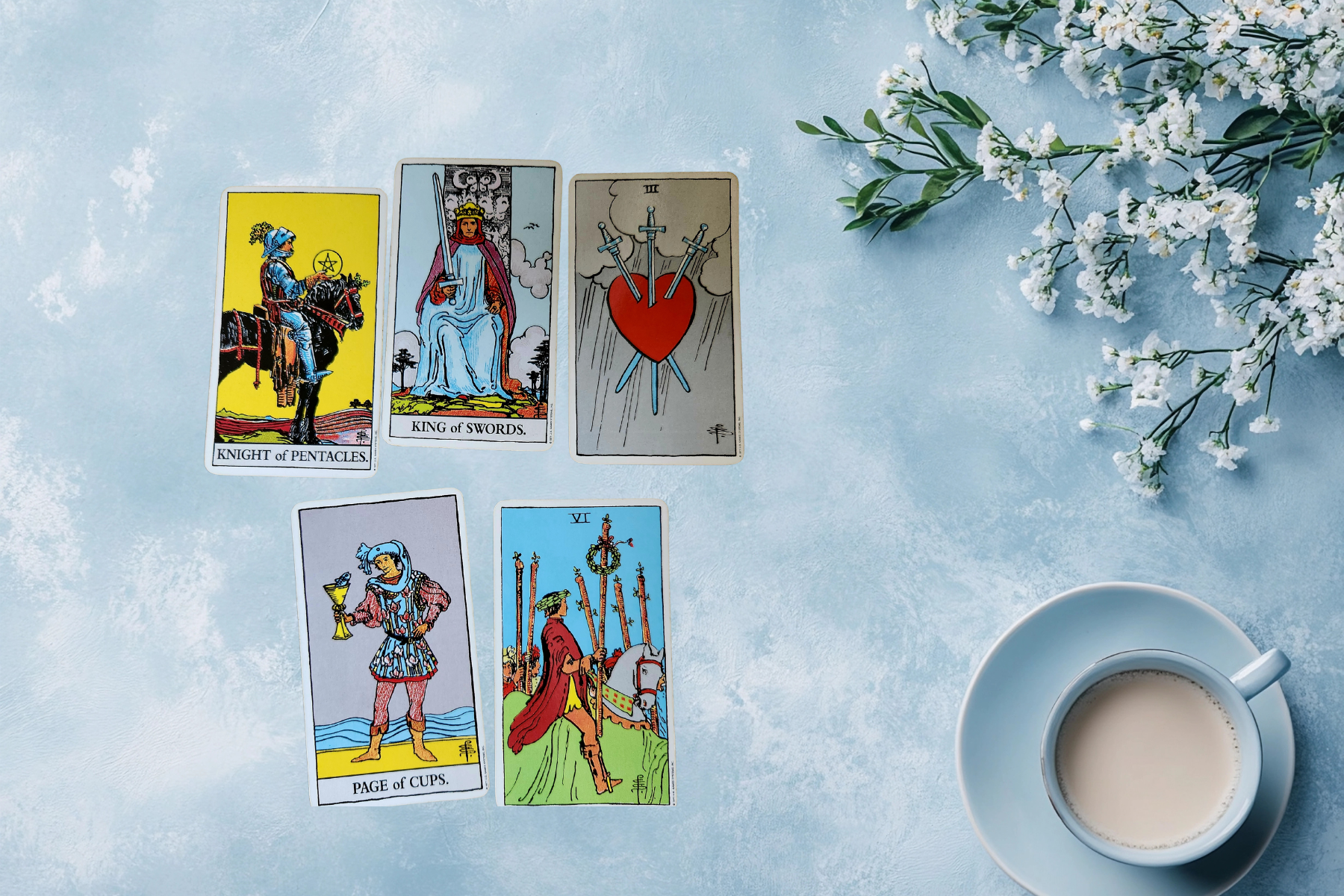 Tarot cards arranged on a soft blue surface with a coffee cup and white blossoms, creating a calm, reflective end-of-week atmosphere