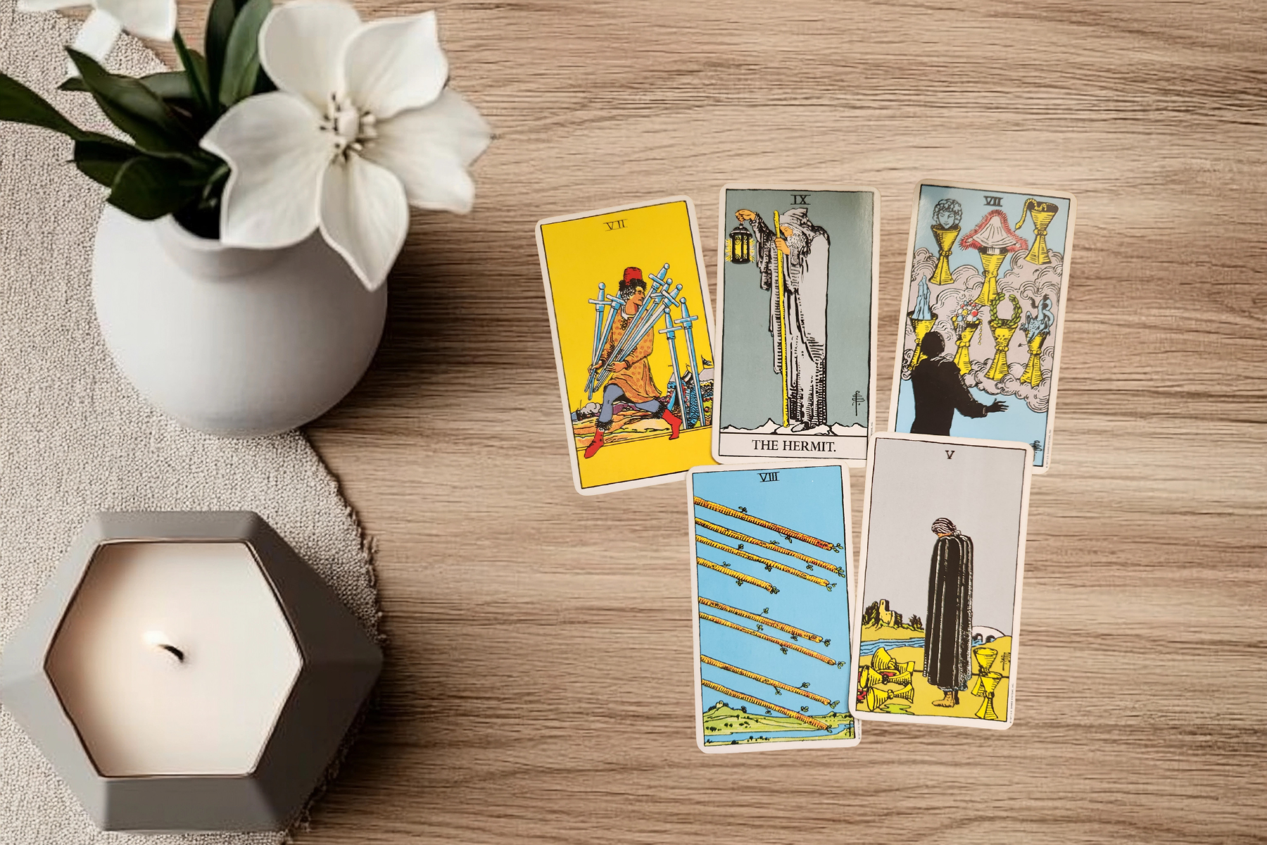 Reading the Rhythm mid-week tarot spread 1 April 2026 featuring Seven of Swords, The Hermit, Seven of Cups, Eight of Wands and Five of Cups on wooden surface with candle and white flower